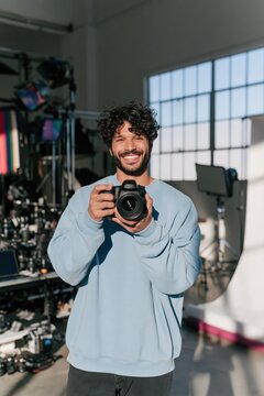 Smiling male photographer with camera in a sunlit studio portrait for social media banner and website background