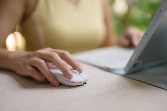 A woman's hand is typing and holding a mouse on a tablet.