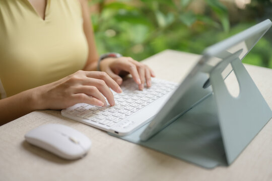 A woman's hand is typing and holding a mouse on a tablet.