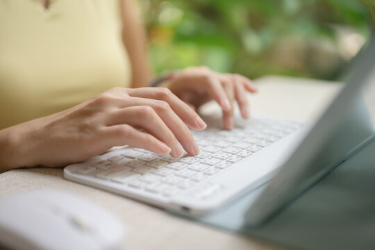 A woman's hand is typing and holding a mouse on a tablet.