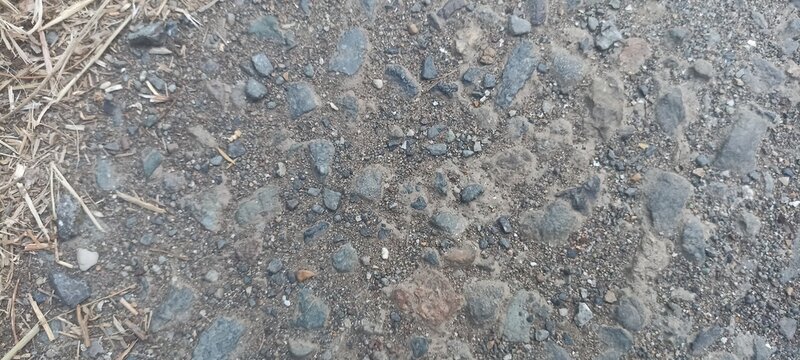 Gravel road texture featuring crushed stone aggregate and dry straw debris, ideal for outdoor environment backgrounds, construction path banners, and landscape design backdrops