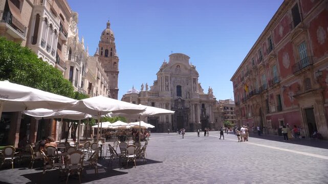 View of Episcopal Palace of Murcia, Cathedral of Murcia and cafes in Placa del Cardenal Belluga on a sunny day, Murcia, Murcia Region, Spain
