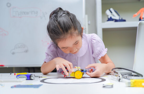Young asian girl focusing on assembly of robotic project for stem education development in classroom