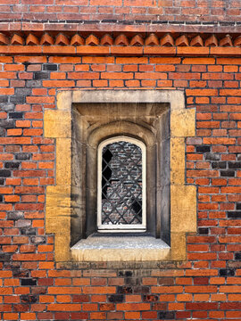 Vintage Arched Window In Red Brick Wall With Stone Masonry Frame And Lattice Pane