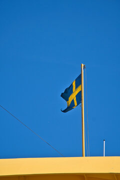 Swedish Flag Waving on Flagpole Against Clear Blue Sky