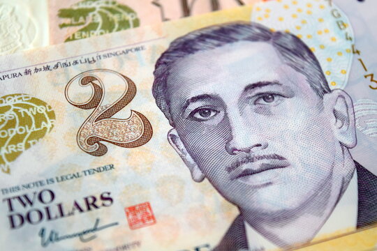 Close-up macro detail of a purple two Singapore dollar (SGD) banknote showing the face value and the portrait of Yusof bin Ishak, the first President of Singapore.