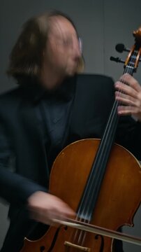 Vertical shot of Caucasian young adult man playing cello passionately with dynamic head movements. Footage is perfect for classical music promotions, artistic talent showcases, or concert ads