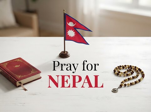 A conceptual image featuring the national flag of nepal, a red book, and prayer beads on a white wooden table with the text pray for nepal