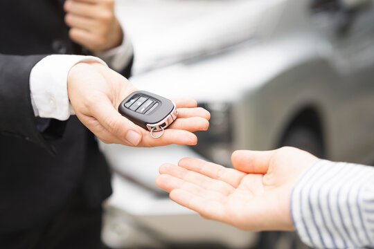 Close up of car dealer rental agent handing remote key to buyer or client leasing new automobile vehicle asset,
customer buying vehicle, car service automotive industry transport and insurance concept