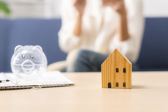 Home savings and mortgage planning concept, wooden house model and piggy bank on desk, representing real estate finance, property investment and future home goals.