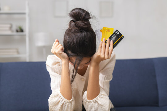 Stressed woman holding credit cards at home, representing credit card debt, financial stress, overspending, payment problems, personal finance, budgeting challenges, money management.