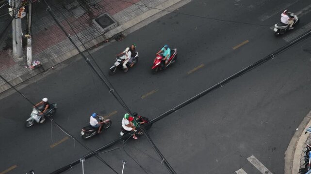Busy urban life with numerous scooters and cars navigating a bustling street crossing in a crowded metropolis. This aerial perspective captures the constant flow of transportation and commuting