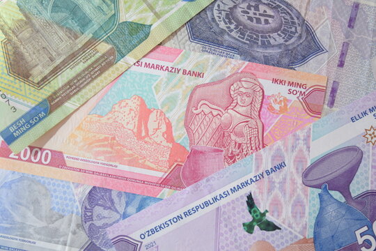 Close up of colorful Uzbekistani som banknotes featuring historical landmarks
