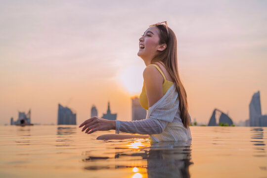 Young cheerful woman laughing at luxury rooftop sunset, embracing pure summer freedom, joy, travel vitality, and wellness lifestyle while relaxing on scenic city holiday getaway.