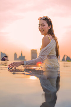 Young cheerful woman laughing at luxury rooftop sunset, embracing pure summer freedom, joy, travel vitality, and wellness lifestyle while relaxing on scenic city holiday getaway.