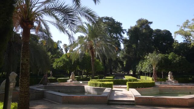 View of trees and fountain in Parque de Mari&shy;a Luisa on a sunny day in Seville Seville, Andalusia, Spain