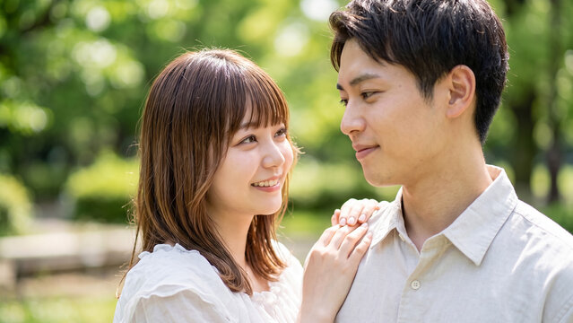 Happy young couple in love looking at each other outdoors in a park, romantic relationship concept