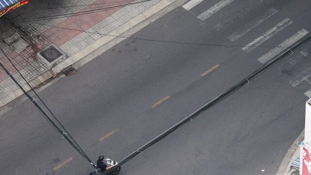 Busy urban life from an aerial perspective showing a constant flow of scooters and motorbikes crossing a street with a crosswalk, representing transportation and daily commutes in an asian city
