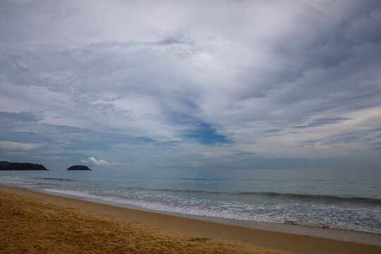 Beautiful tropical beach view with golden sand ocean waves and green hills