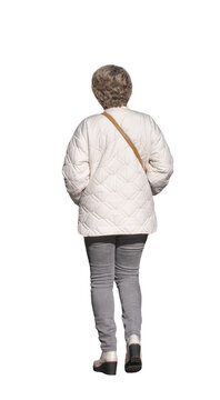 Femme senior vue de dos qui marche, portant une veste matelass&eacute;e blanche, un jean gris et un sac en bandouli&egrave;re, les mains dans les poches de sa veste, attitude d&eacute;contract&eacute;e, promenade automnale