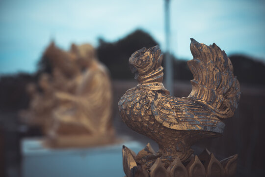 Close-up of a weathered golden bird sculpture at a traditional Buddhist temple