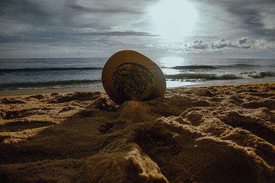 Stylish straw hat on the sand against the backdrop of the sea and sunset sky