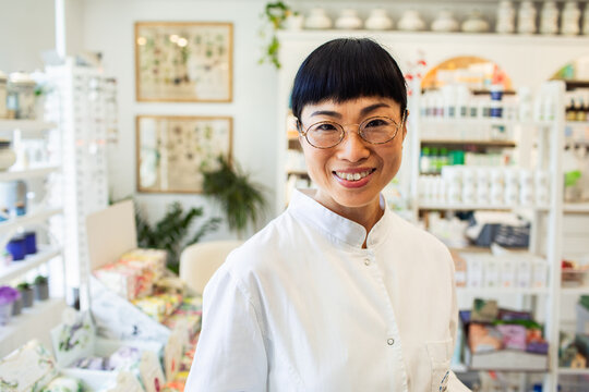 Smiling pharmacist with glasses in bright apothecary shop