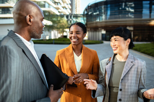 Three business professionals networking outdoors in modern city