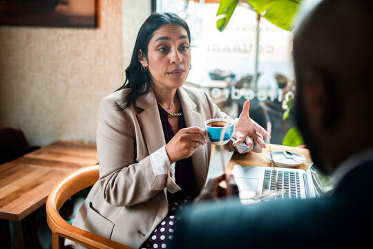 Business professionals discussing project over coffee in cafe