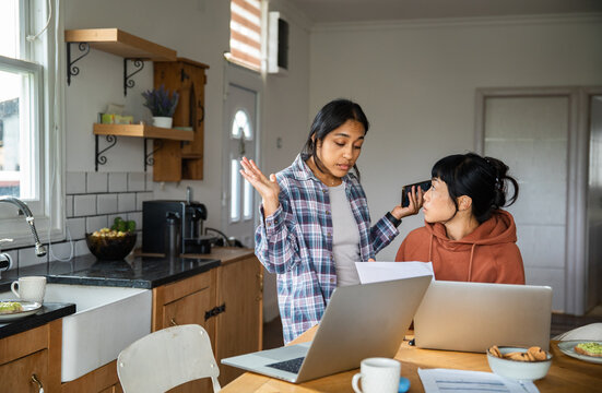 Two women discussing household finances at kitchen table