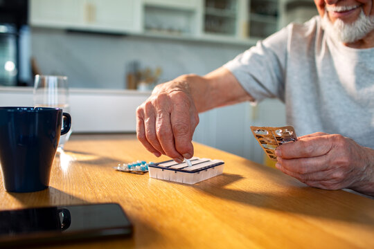Senior man organizing medications at home kitchen table
