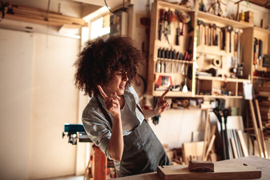 Young craftswoman dancing in sunny woodworking workshop