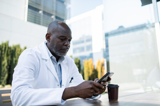 Doctor using smartphone outside modern hospital