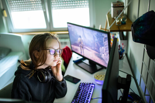 Teen gamer wearing headset playing pc at home desk