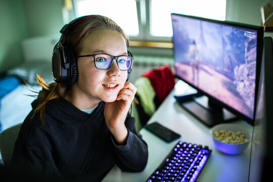 Teen girl gamer with headset playing pc at home desk