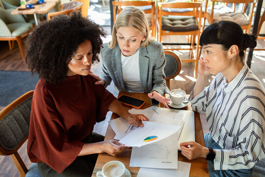 Three businesswomen discussing financial report at cafe