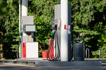 Coiled fuel hoses hang unused from a pump island, the point where wholesale energy markets finally turn into a number a driver reads on a forecourt display. © K
