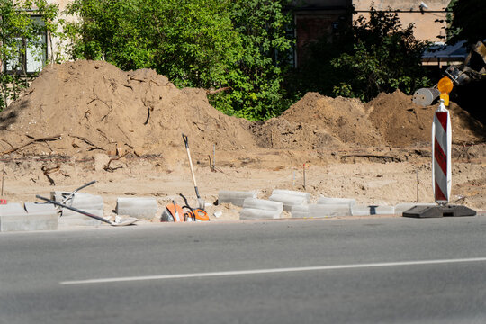 A dug-up verge waits for the next phase of the works, spoil on one side and new concrete edging laid out ready along the exposed and weathered subgrade.