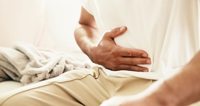Hands, person and stomach ache in home, pain or uncomfortable with irritable bowel syndrome. Sick, abdomen inflammation or man with constipation, gas bloating or diarrhea problem with food poisoning