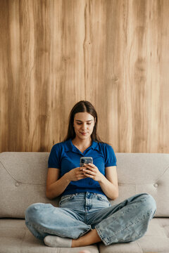 Woman relaxing on sofa using mobile phone
