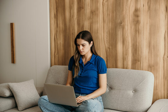 Woman working from home using laptop on sofa