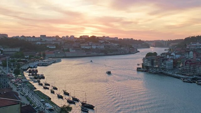 Sunset view of Douro River, Ribeira do Porto, Portugal, and Vila Nova de Gaia with tourist boats crossing the river and moored rabelo boats by the quay