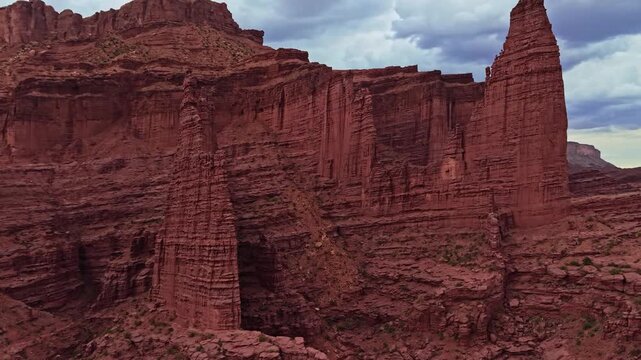 Panoramic aerial flight beside dramatic sandstone Fisher Towers overcast evening skies near Moab Utah