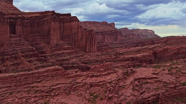 Panoramic aerial flight beside dramatic sandstone Fisher Towers overcast evening skies near Moab Utah
