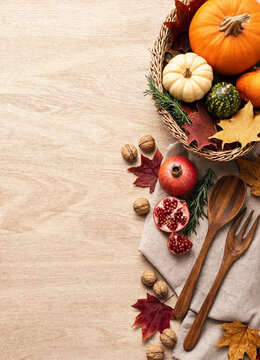 Autumn harvest composition with pumpkins, pomegranates and wooden cutlery on wooden background