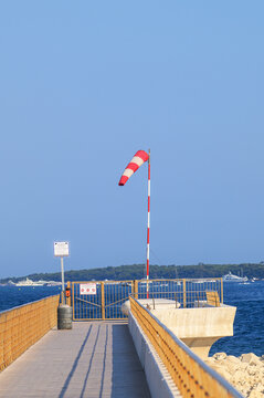 Red and white windsock on a pier above the blue Mediterranean Sea