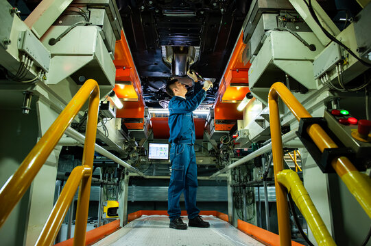 Auto Worker Inspecting Car Chassis