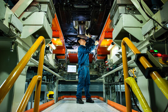 Auto Worker Inspecting Car Chassis