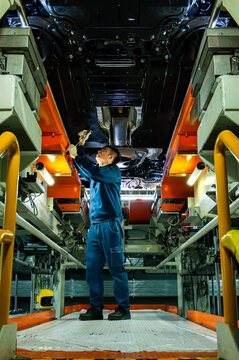 Auto Worker Inspecting Car Chassis