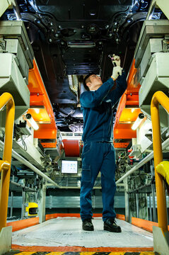 Auto Worker Inspecting Car Chassis